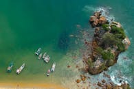 鸟瞰图：小船漂浮在岩石海岸线和碧绿水域附近