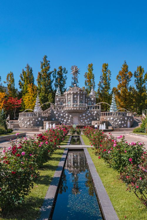 Free Beautiful stone garden with symmetrical flower beds and a reflective canal under a bright blue sky. Stock Photo