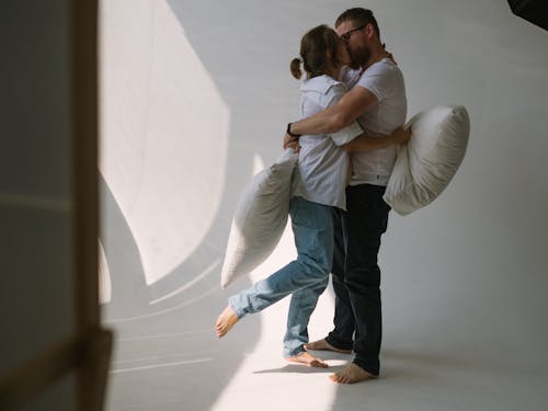 Couple Holding Pillows and Kissing