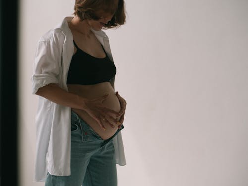Pregnant Woman in Black Brassiere and Blue Denim Jeans