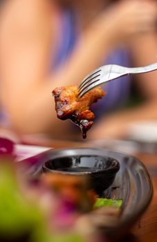Close-up of a fork holding a juicy chicken piece, ready to dip in sauce, capturing culinary delight.