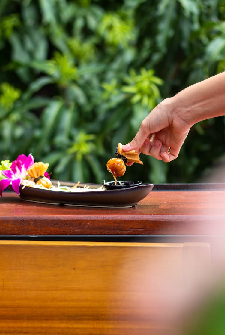 Hand Dipping Wonton In Sauce