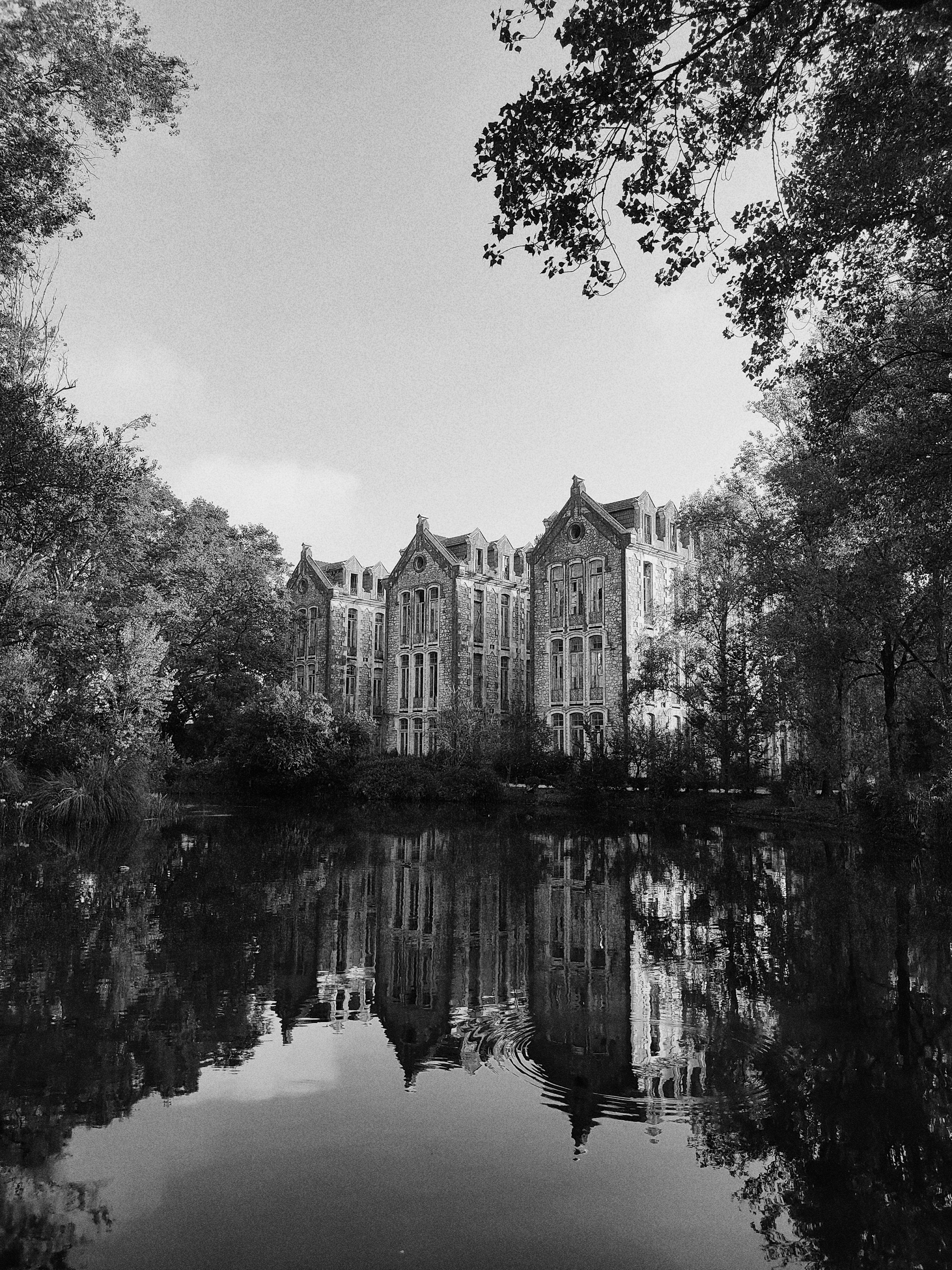 grayscale photo of a building near a river