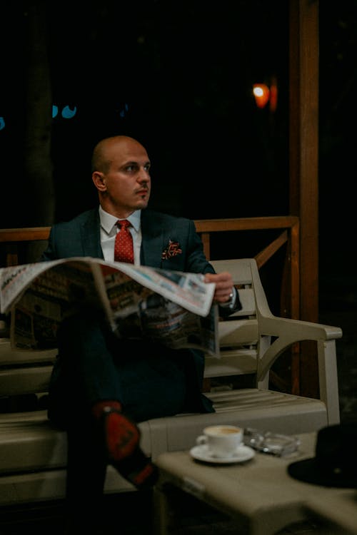 Photo of an Elegant Man Reading a Newspaper with His Coffee