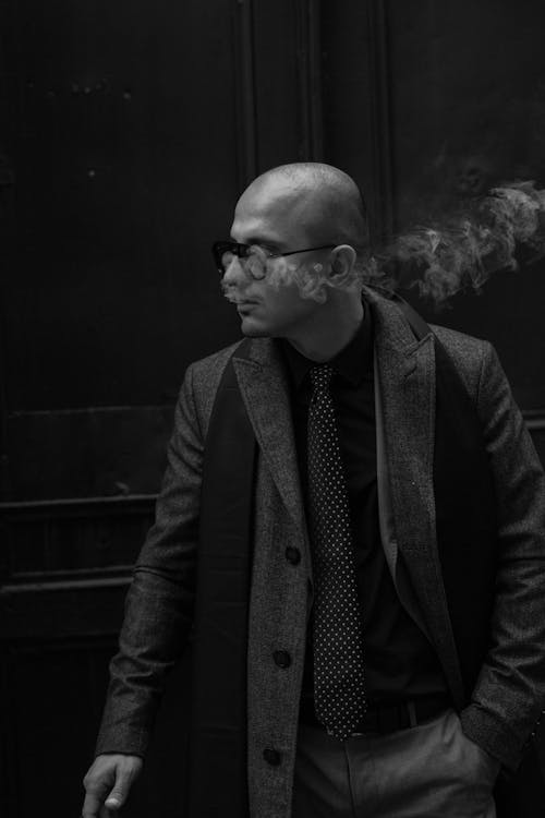 A Grayscale Photo of a Bald Man Smoking