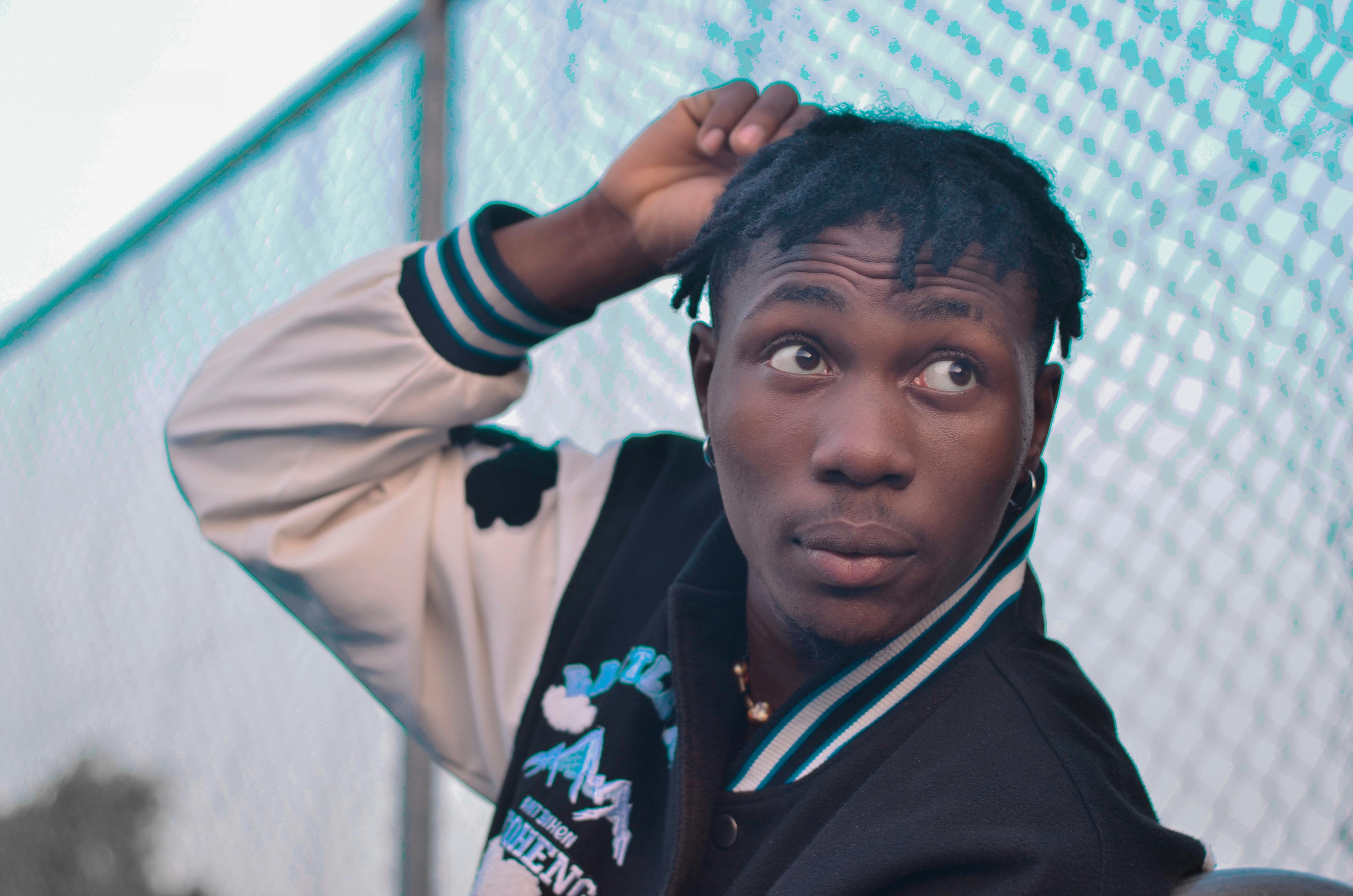 Stylish portrait of an African American man with dreadlocks wearing a varsity jacket.