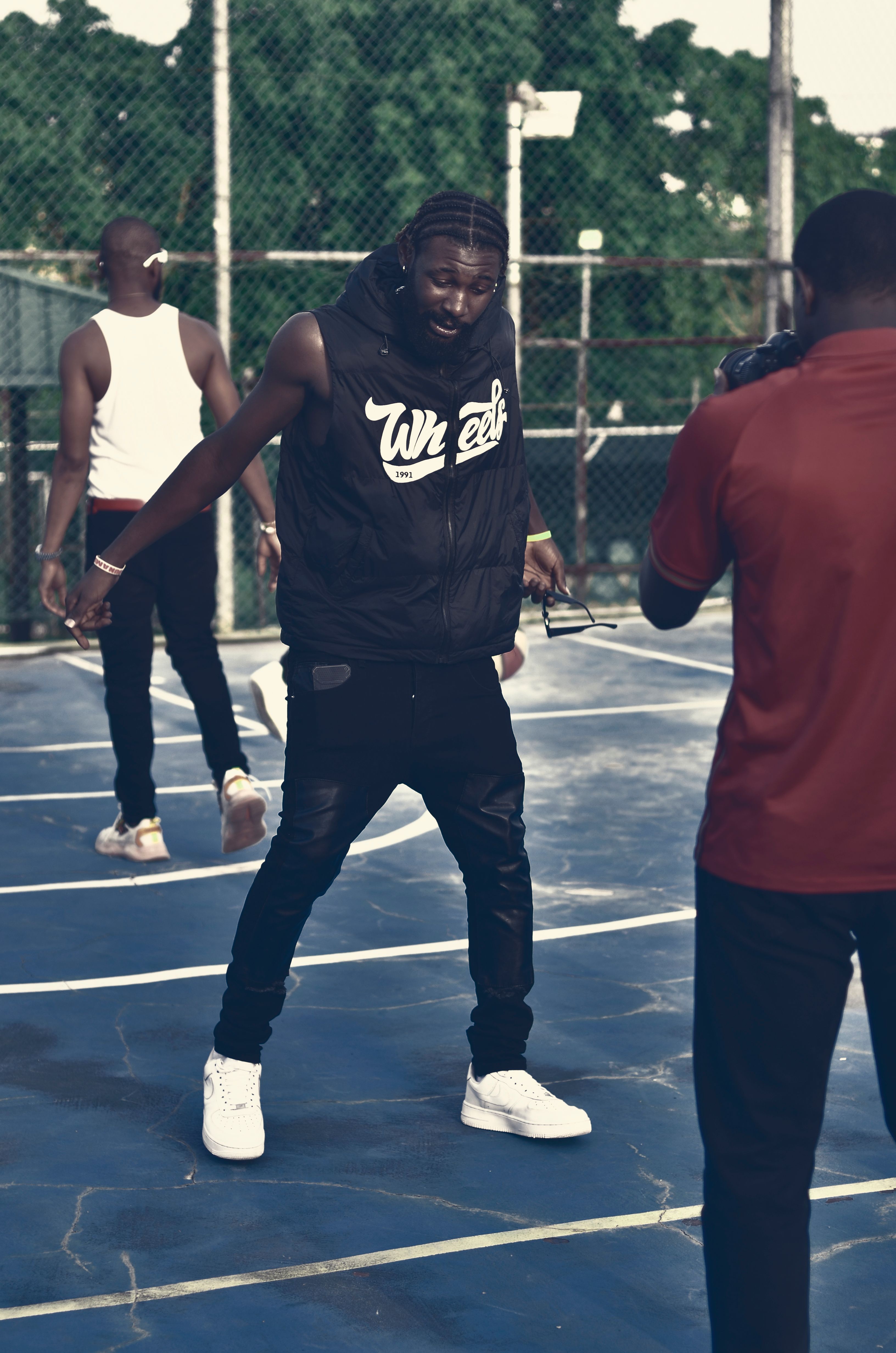 Three young men in sportswear posing on an outdoor basketball court, captured during a photo session.