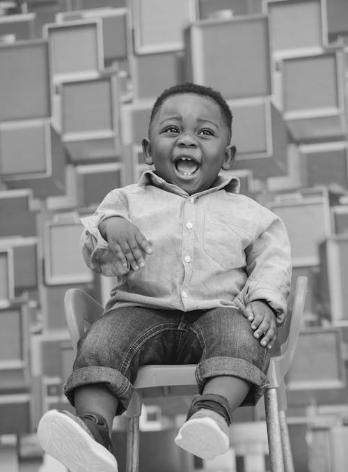 Free Laughing Boy in Shirt Sitting on Chair Stock Photo