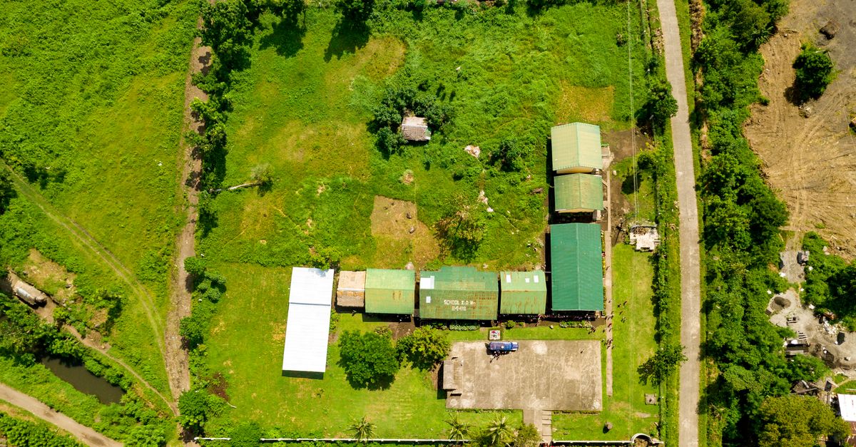 Aerial shot showcasing rural farmland with buildings, roads, and greenery.