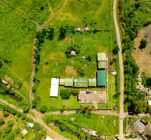 Free Aerial shot showcasing rural farmland with buildings, roads, and greenery. Stock Photo