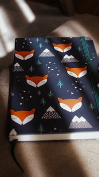 Close-up of a notebook with a fox and mountain pattern, illuminated by natural sunlight.
