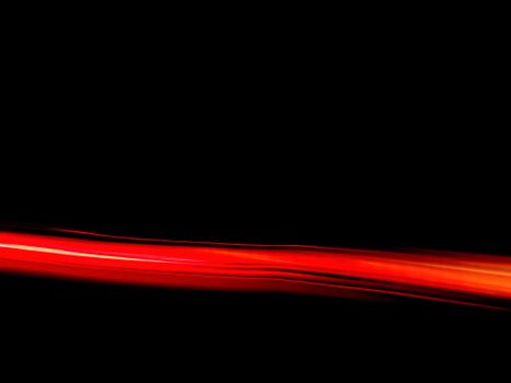 Dynamic red light streak on a black backdrop creating an abstract visual effect.