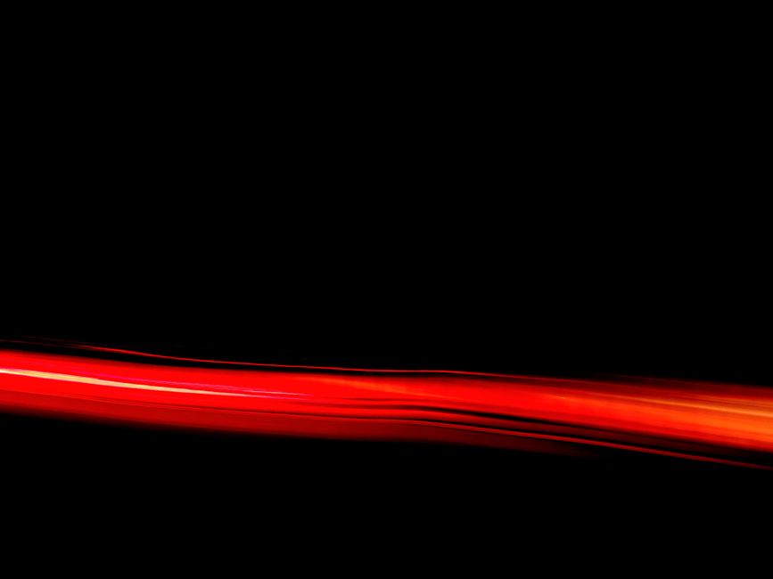 Dynamic red light streak on a black backdrop creating an abstract visual effect.