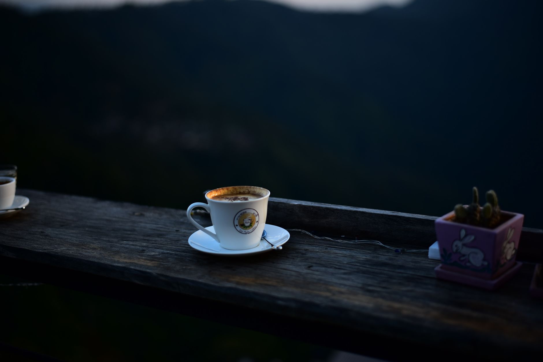 A relaxing cup of coffee on a balcony overlooking scenic mountains at dusk.