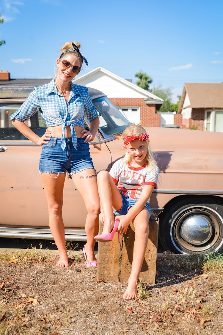 Smiling Mother And Daughter Posing Near Car