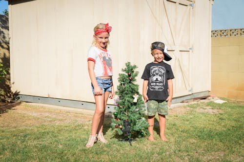 Free Boy and a Girl Standing near Christmas Tree Stock Photo