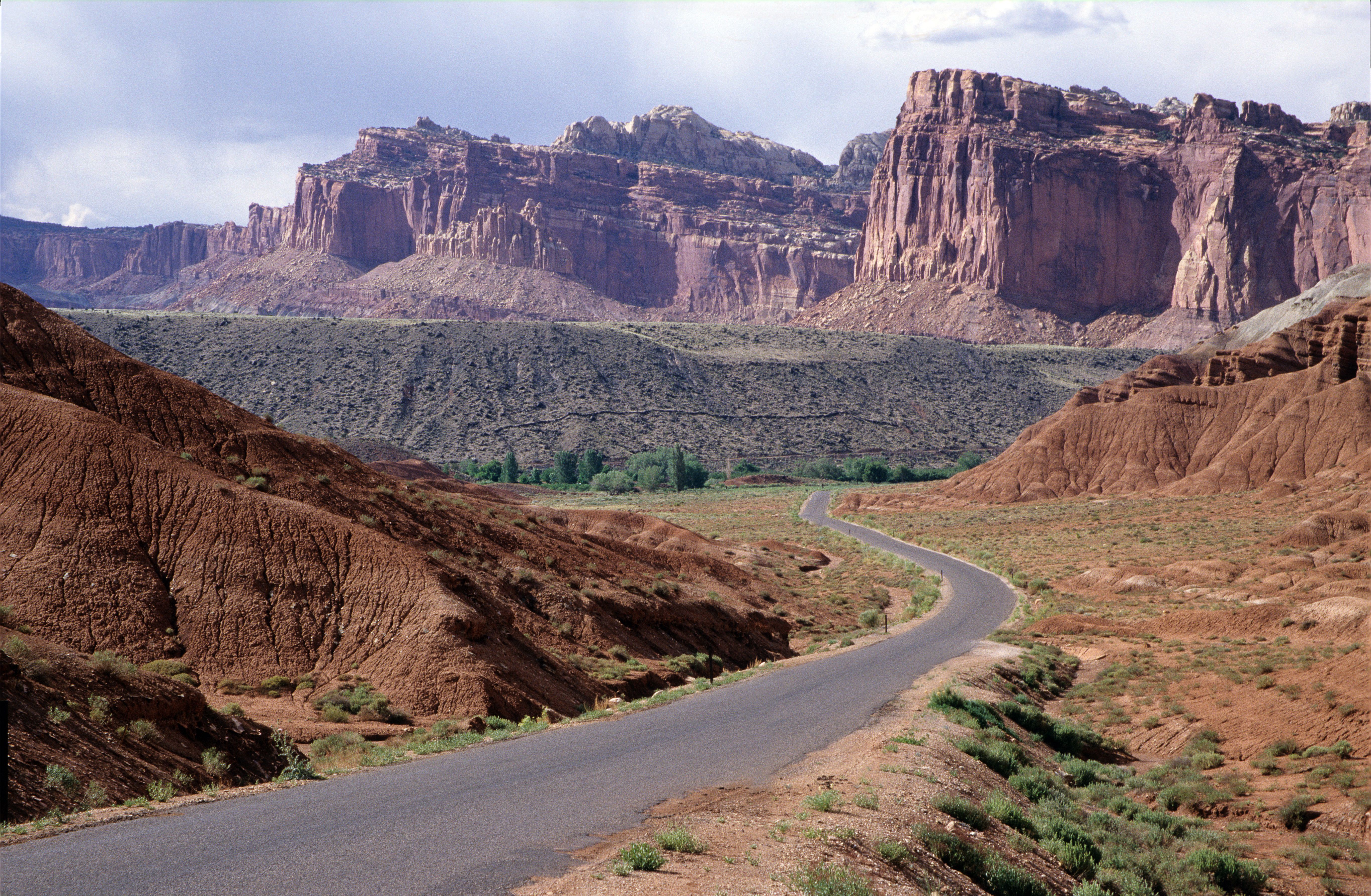 A winding road in Capitol Reef National Park showcasing the rugged red rock cliffs and desert landscape.
