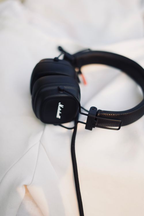 Free High-quality black headphones resting on a soft white fabric surface. Stock Photo
