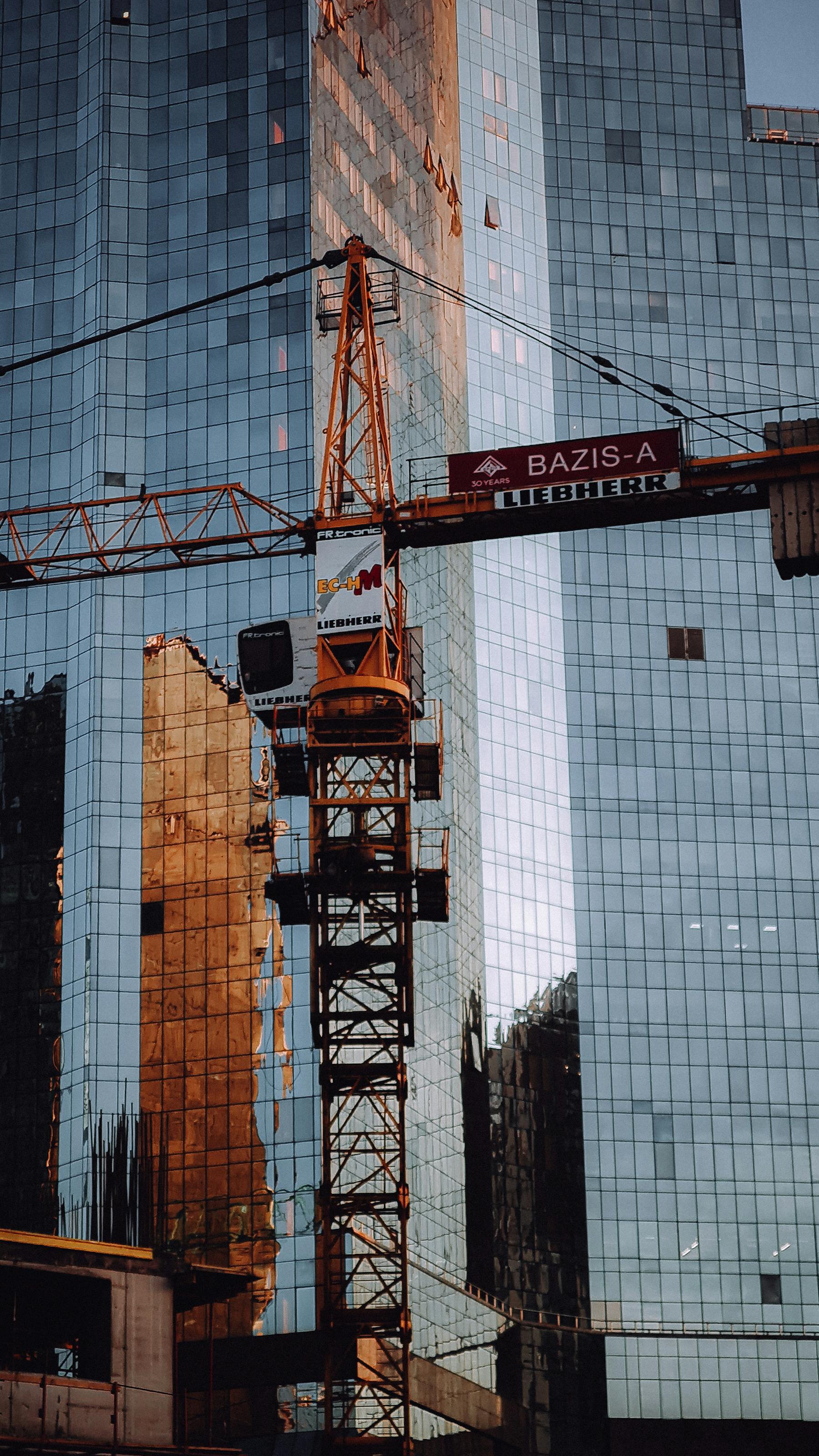 Tower crane operating beside a high-rise construction project
