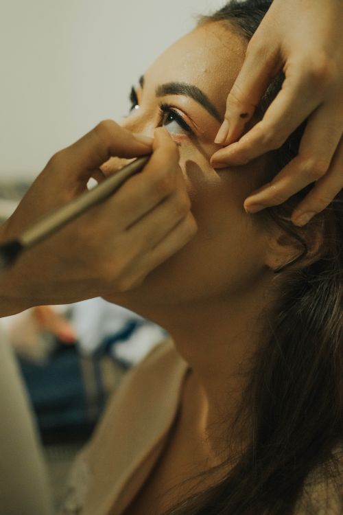 Free A young woman getting eye makeup applied by an artist. Stock Photo