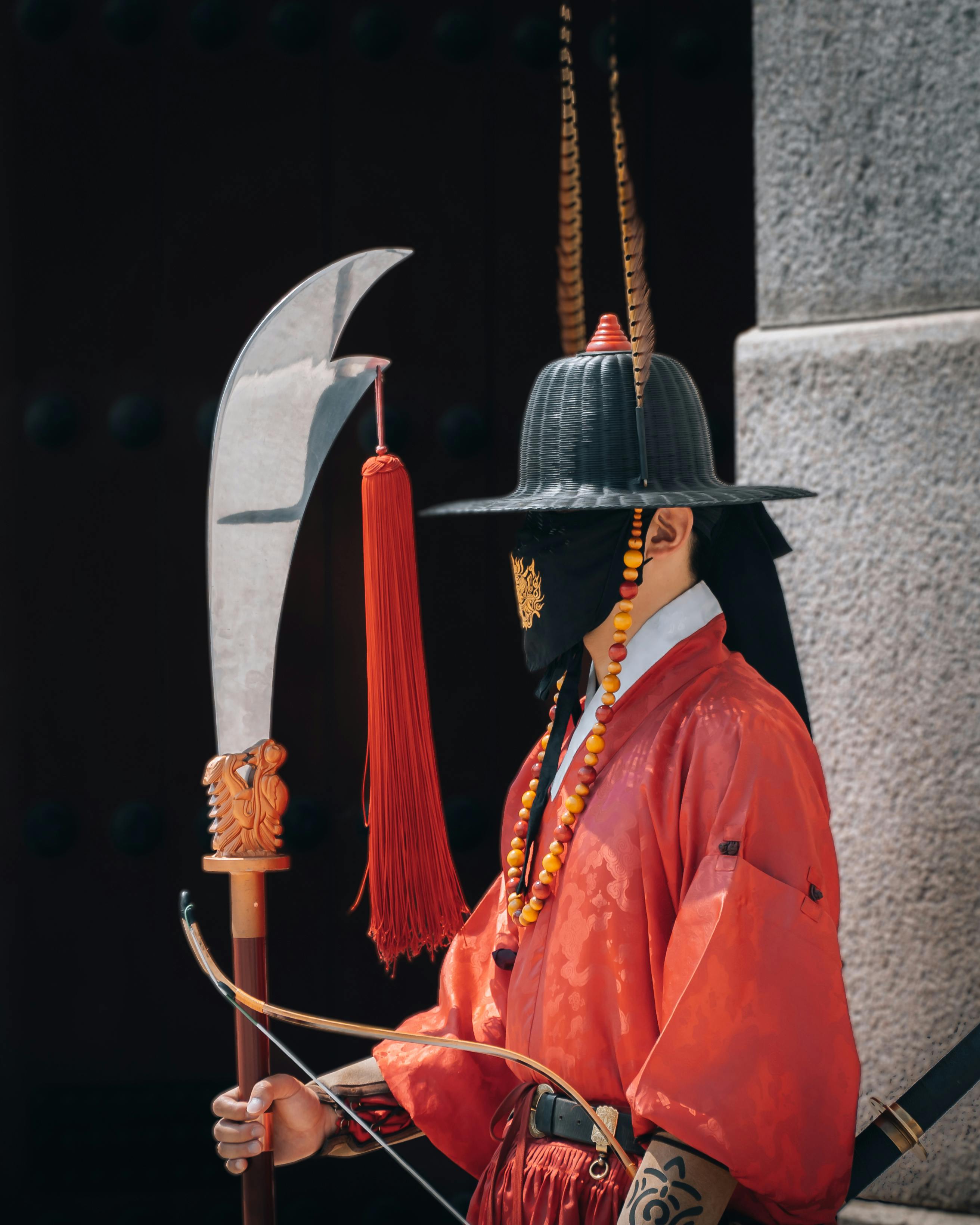 man in a costume with a red gown hat and fabric covering his face holding sword