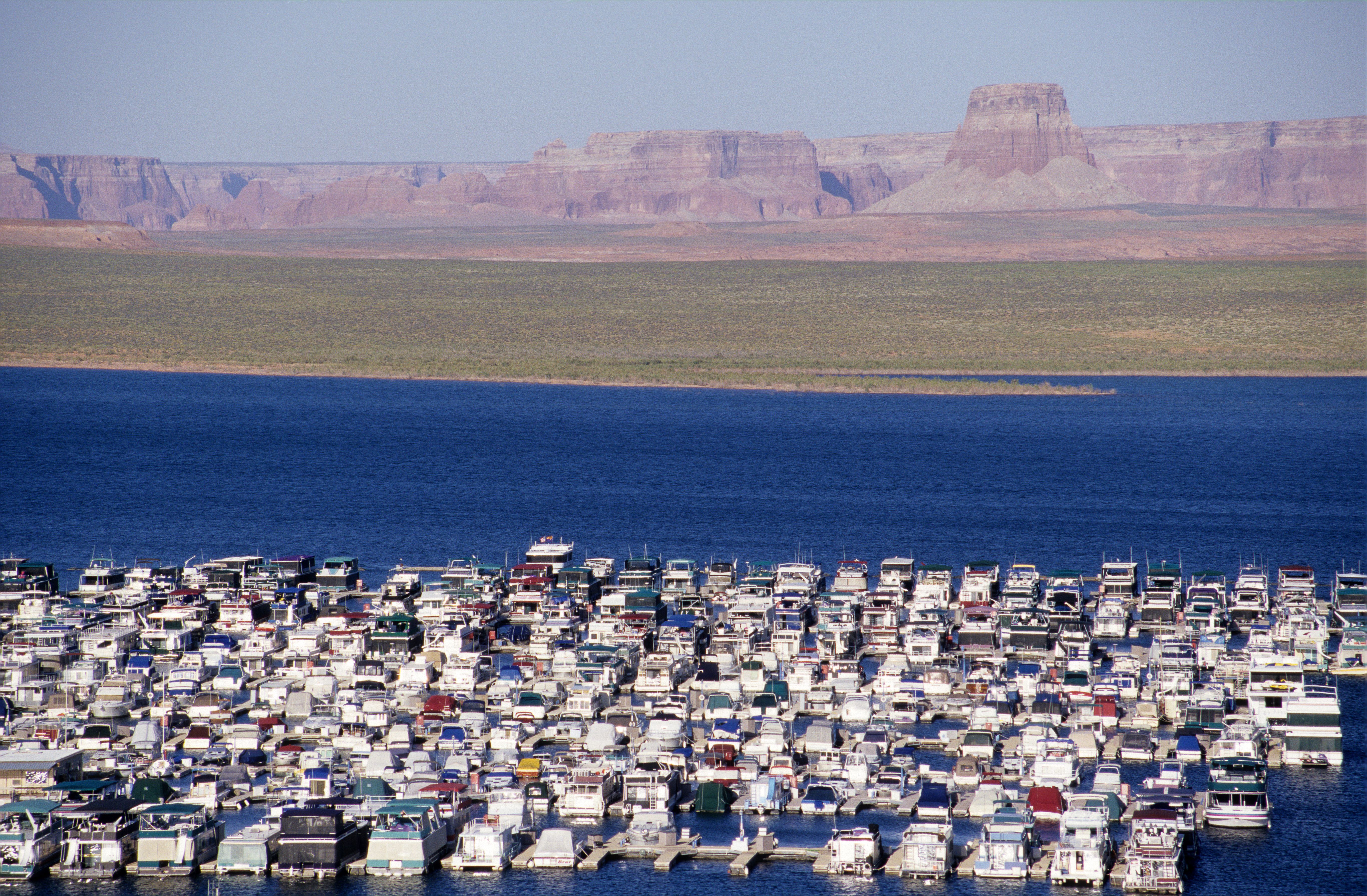 Aerial view of moored houseboats on Lake Powell with sandstone formations and desert landscape in Page, Arizona.