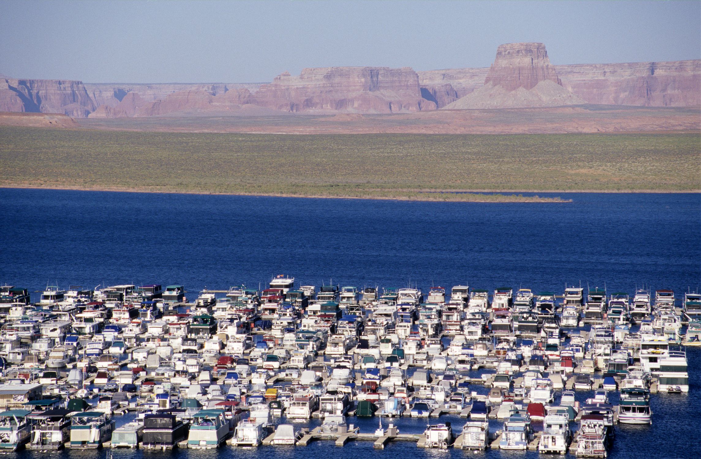 Aerial view of moored houseboats on Lake Powell with sandstone formations and desert landscape in Page, Arizona.