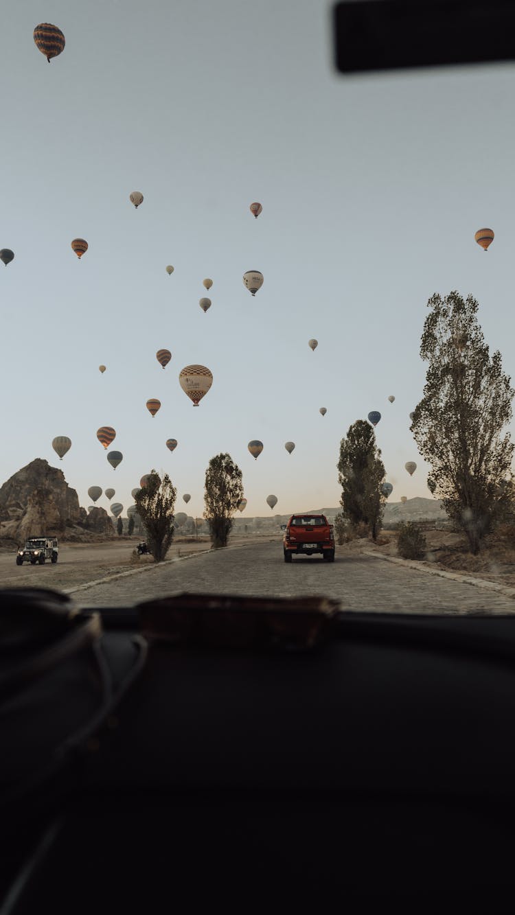 Hot Air Balloons Flying Over A Car On A Road