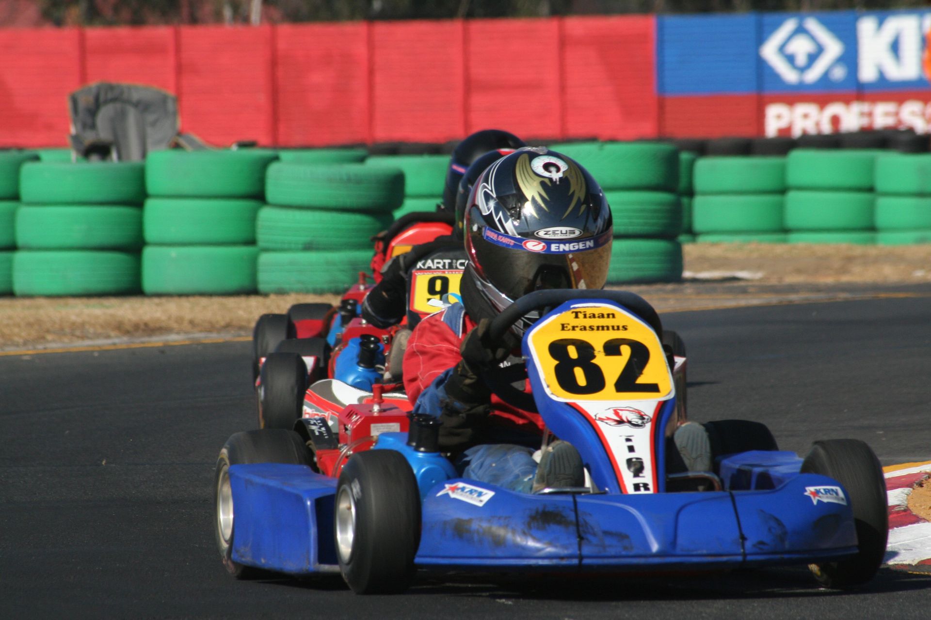 Competitive go-kart racing featuring young drivers on a dynamic track turn.
