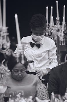 Elegant event with waitress pouring wine, captured in black and white.