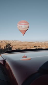 A hot air balloon soars above the unique landscape of Göreme, Turkey, during a clear day.