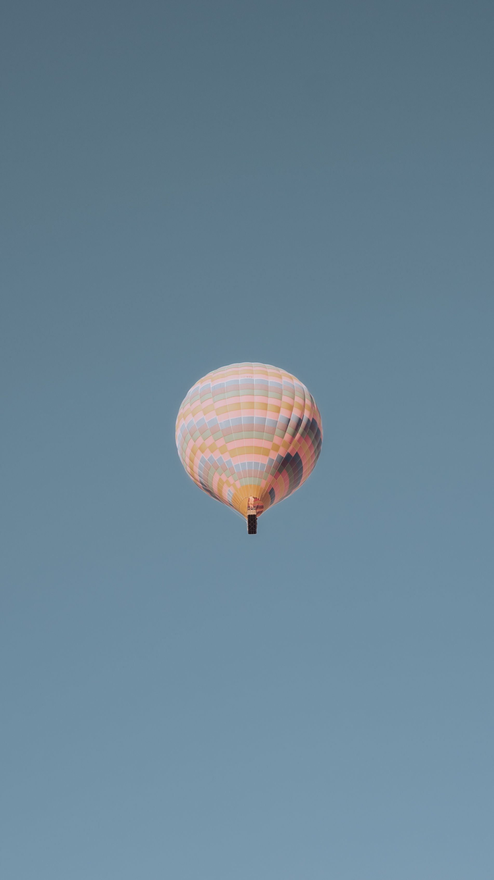 A vibrant hot air balloon soars against a clear blue sky in Göreme, Turkey.