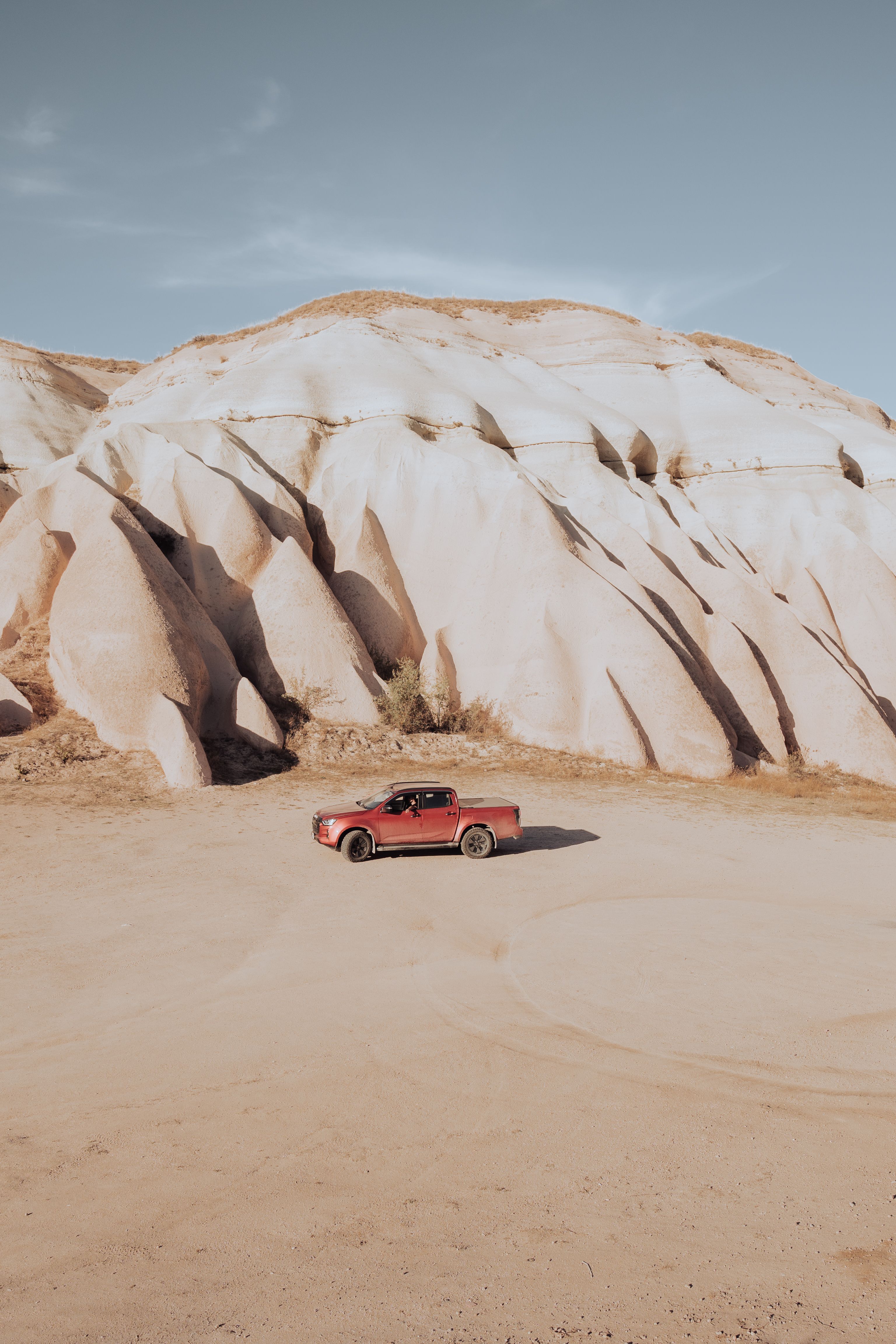 A red pickup truck parked against Göreme's unique eroded rock formations in Turkey.