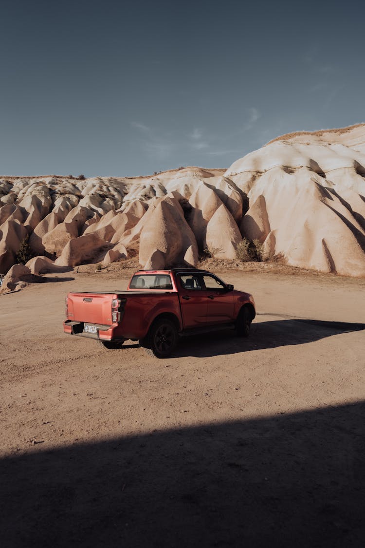 A Red Pick Up Truck Parked Near The Rock Formations