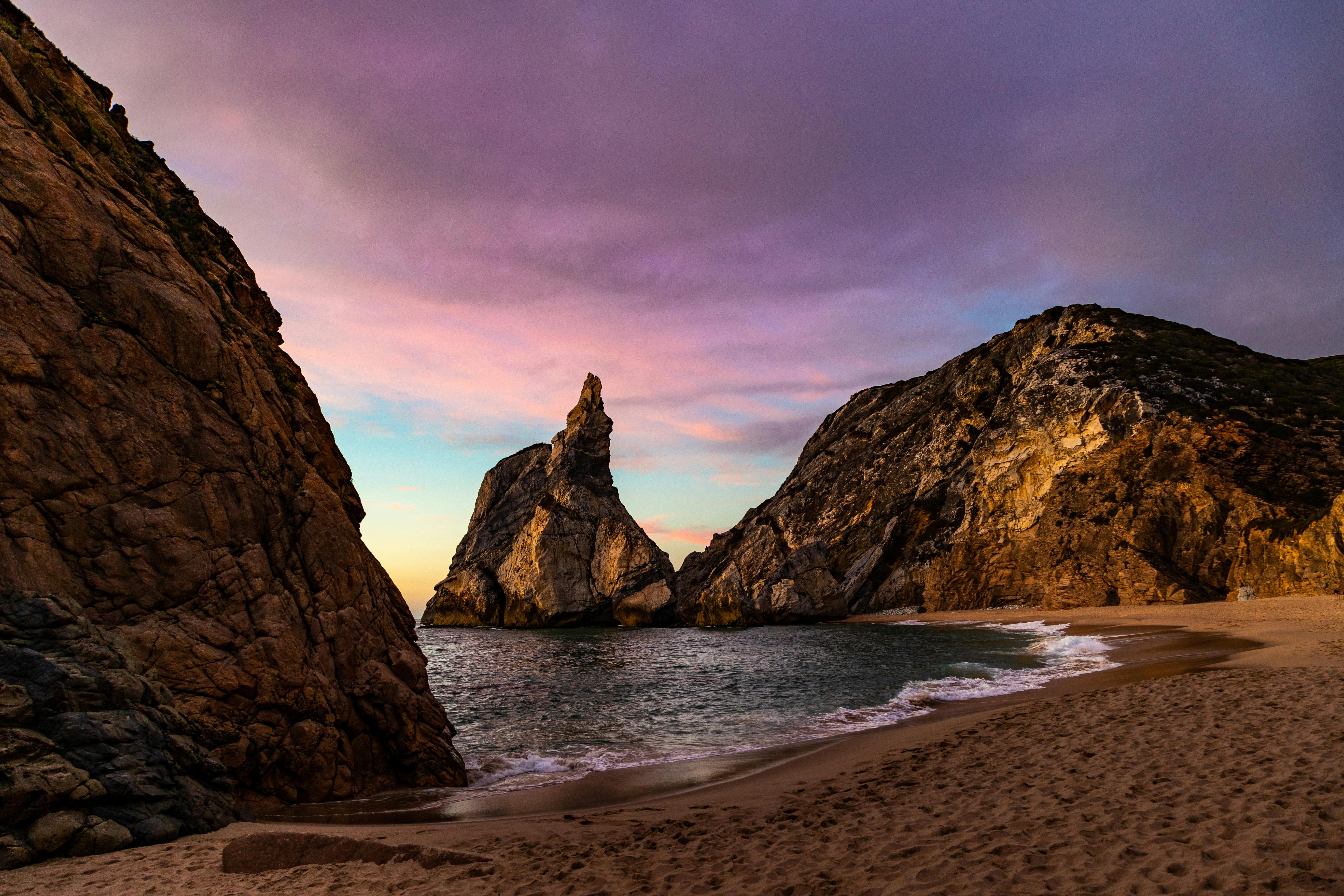 Captivating beach view at sunset with striking rock formations and pastel sky.