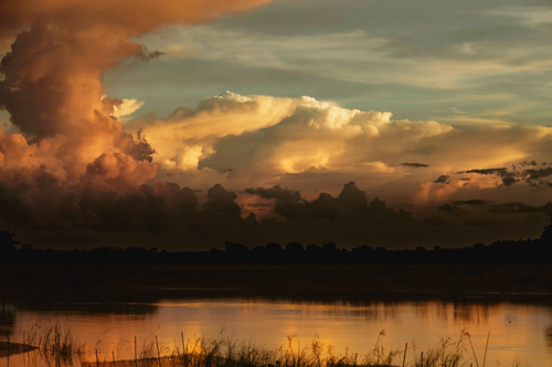 Free Stunning sunset with vibrant clouds reflecting on water in Chapai Nawabganj, Bangladesh. Stock Photo