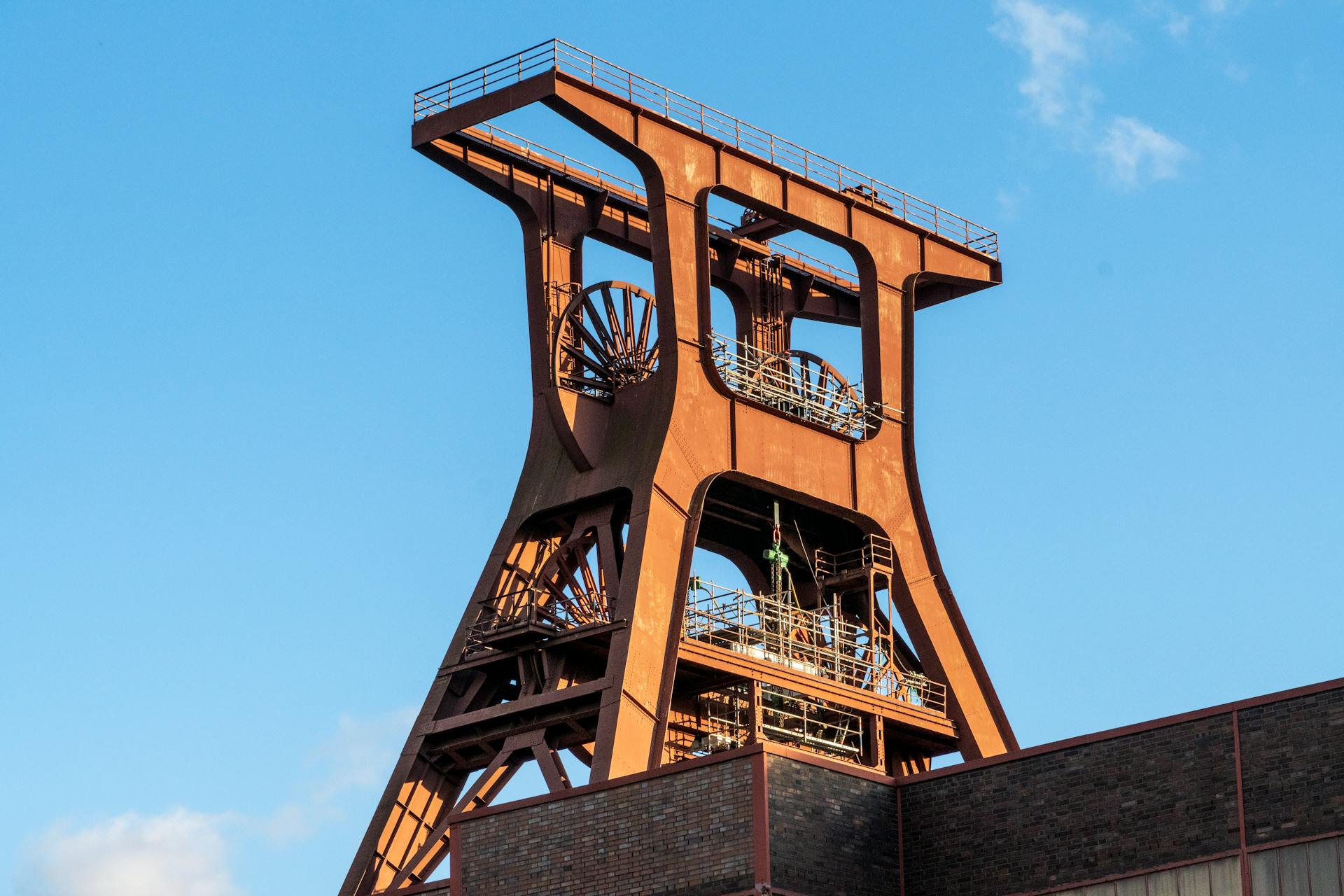 A detailed view of an old rusted industrial mine structure under a clear blue sky, showcasing robust engineering.