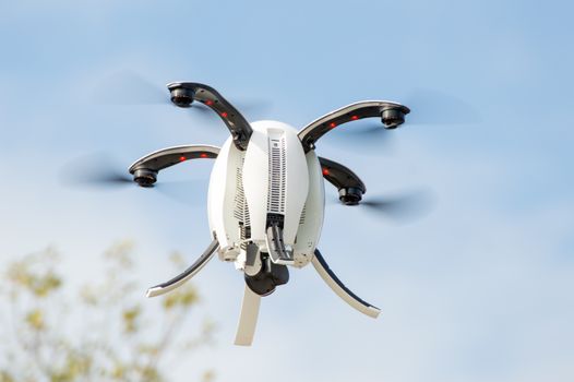White drone flying against a clear blue sky, showcasing advanced technology.