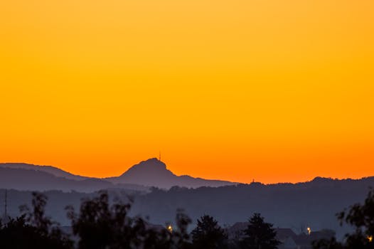 Captivating mountain silhouette against a vibrant orange and yellow sunset sky.