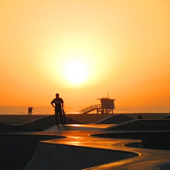 Skater silhouette against a vibrant sunset at Venice Beach, Los Angeles.