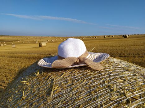 White wide brimmed hat on straw bale in sunny Czech field.