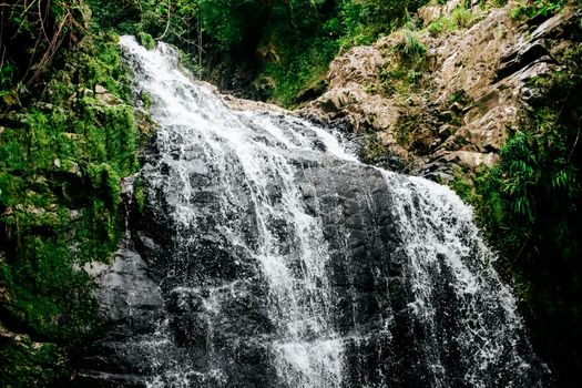 A mesmerizing waterfall cascading over lush green rocks in a natural outdoor setting.