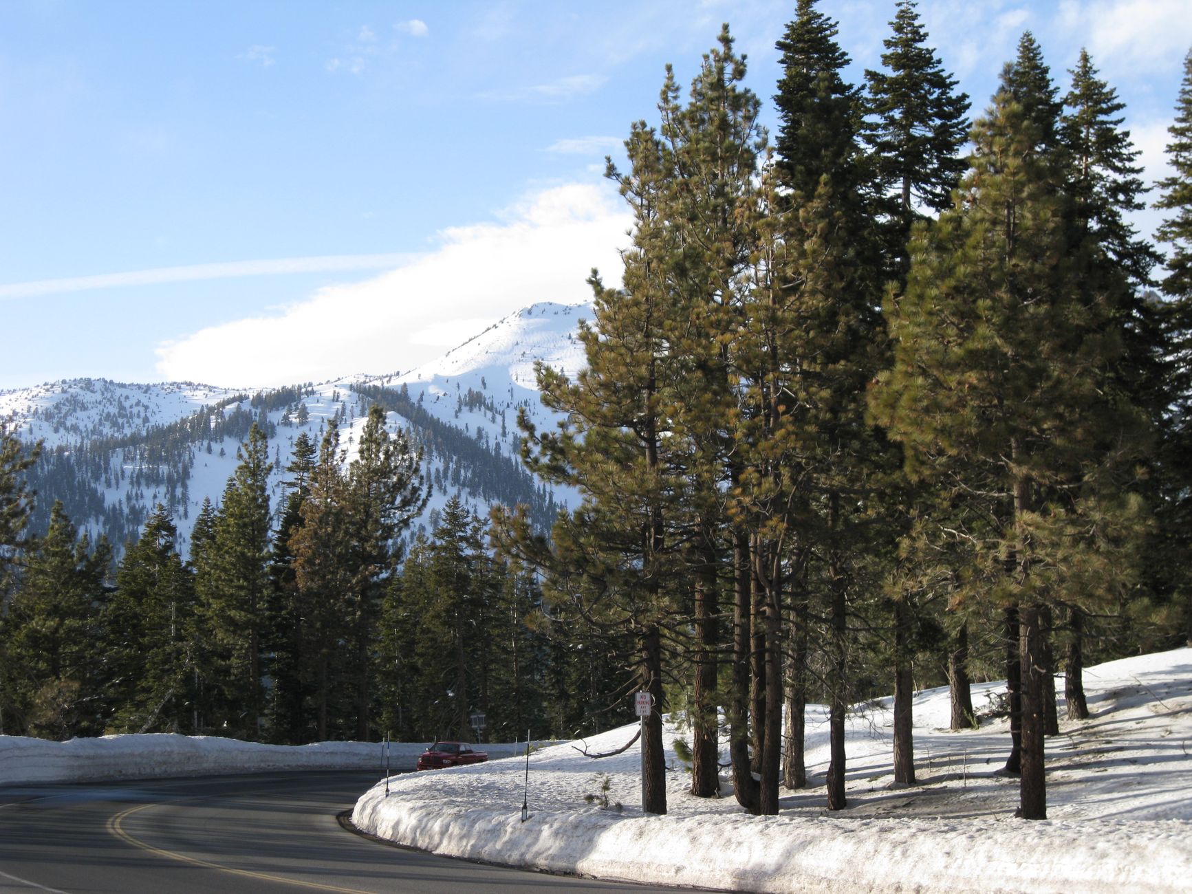 A picturesque winter scene with snow-covered trees and mountains along a road in South Lake Tahoe, California.