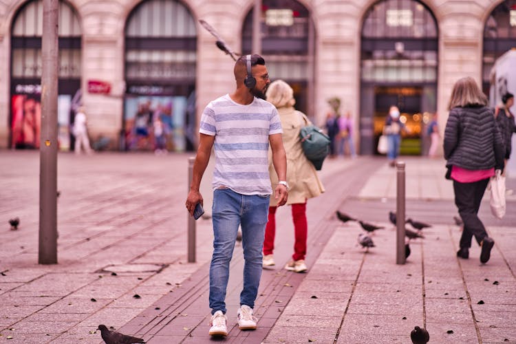 Man Wearing Headphones Walking Through Plaza