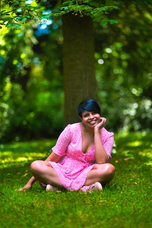 Free A cheerful woman in a pink dress enjoying a sunny day outdoors. Stock Photo