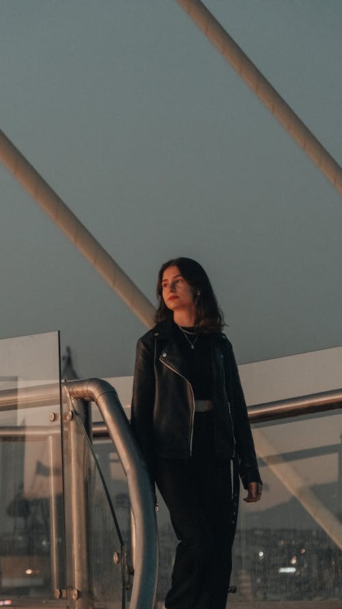 A Woman in Black Leather Jacket Standing Near the Metal Railing