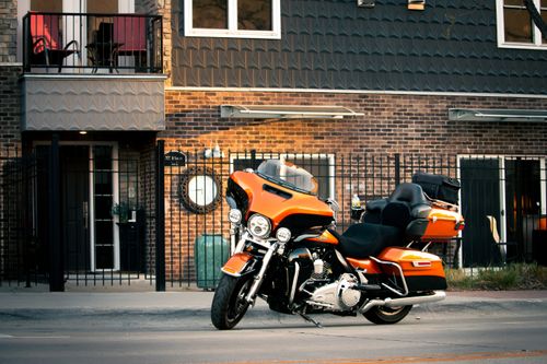Free Vibrant orange motorcycle parked in front of a brick building in Lincoln, NE. Stock Photo