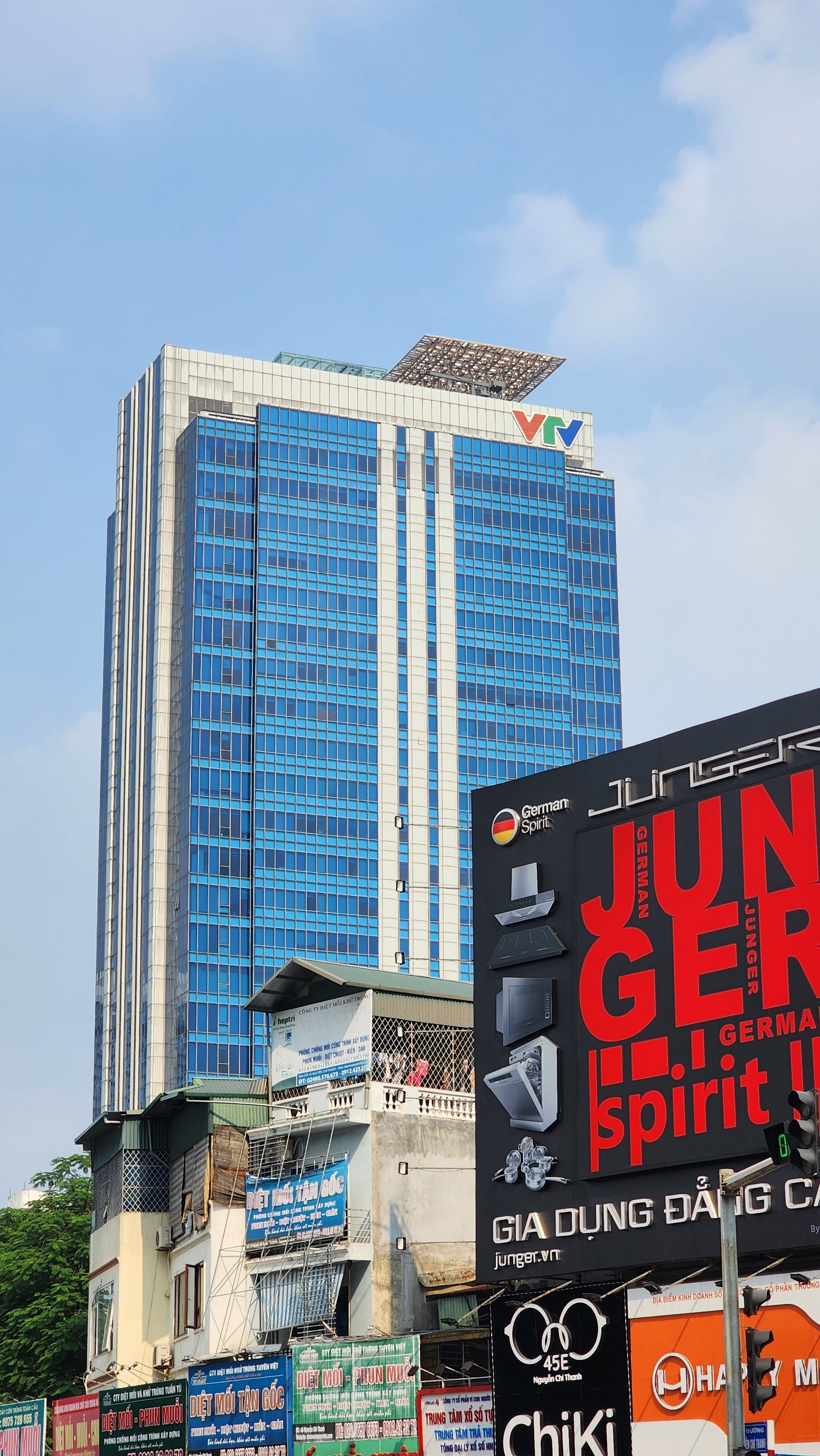 High-rise building with glass facade in Láng Hạ, Hanoi featuring vibrant advertisements in the foreground.