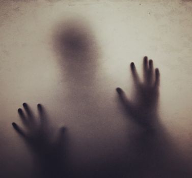 Eerie silhouette of hands pressing against foggy glass, evoking mystery and suspense.
