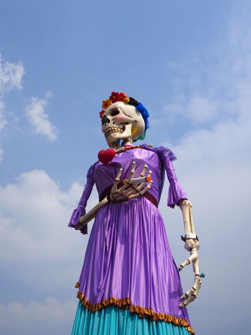 Free Vibrant skeleton statue with purple dress celebrating Dia de los Muertos under a blue sky. Stock Photo
